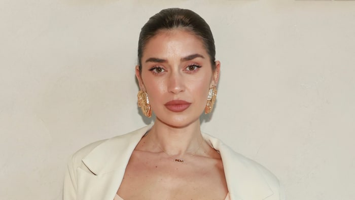 Nicole Williams English poses in a cream-colored corset top, a matching blazer and oversized gold earrings.